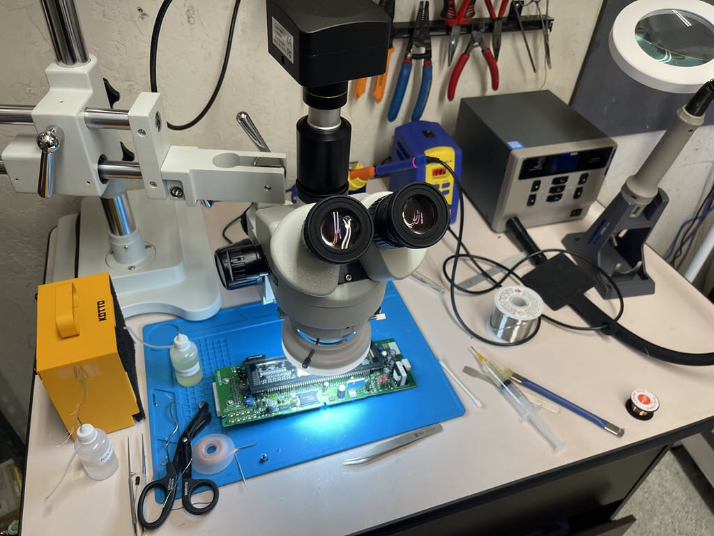 Electronics repair station with a microscope, soldering station, hot air station, fume extractor, and Prius combination meter circuit board being repaired