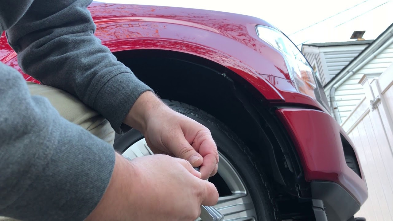 Mechanic accessing headlight through the wheel well